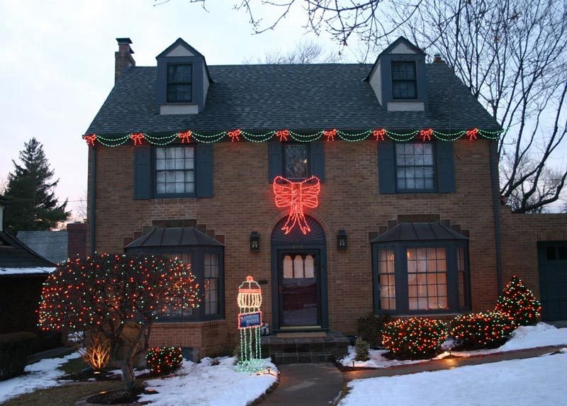 Traditional home with garland and a red holiday bow along the roofline